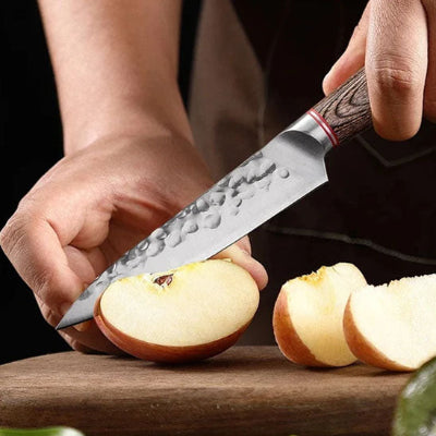 couteau de cuisine manche bois martele coupant une pomme sur planche bois