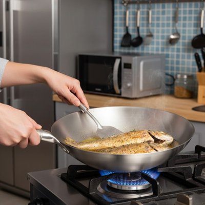  Poele wok en acier inoxydable sur gaz cuisson poisson tenue par une main
