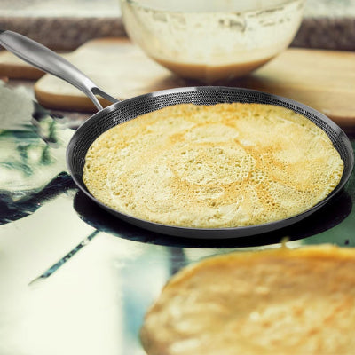 poele a crepe sur une table avec une crepe bien cuite a l'interieur