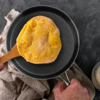 poele a crepe vue de haut avec alveoles et une crepe sur sparule en bois