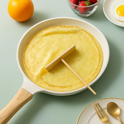 poele_a_crepe_pour_induction sur table avec des fruits et un couvert dore autour