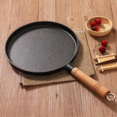 poele a crepes en fonte sur table en bois avec des cerises dans un bol