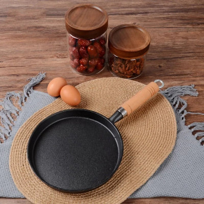 poele a crepes en fonte sur table en bois avec deux pots de fruits secs