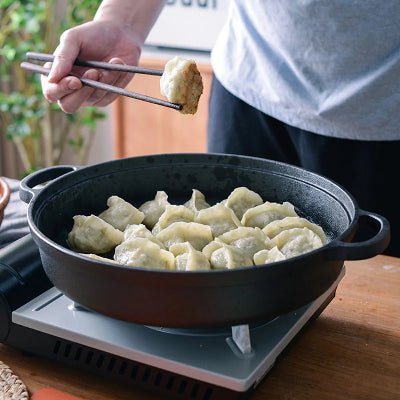poele en fonte avec des ravioli chinois sur cuisinire à gaz