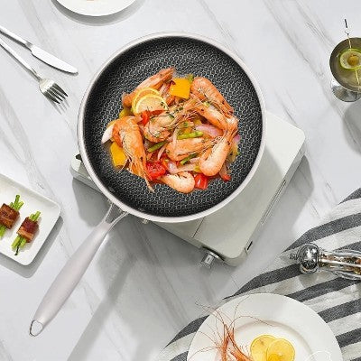 poele_en_inox_antiadhesive avec couvercle en verre trempe sur table cuisine adresse avec crevettes cuites dedans